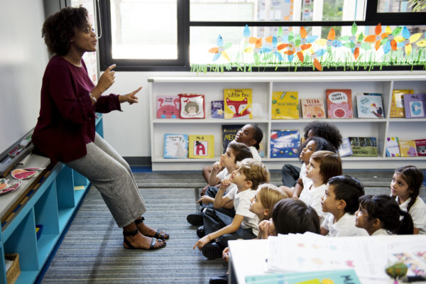 Kindergarten students sitting on the floor listening to teacher