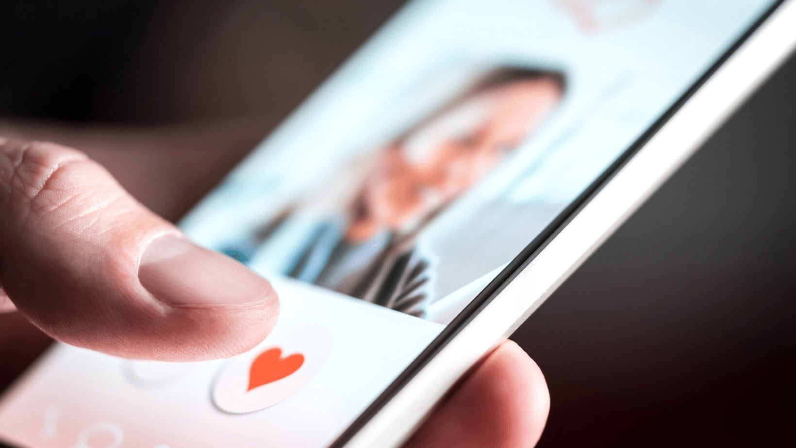 Close-up of hand holding smartphone with dating app profile.