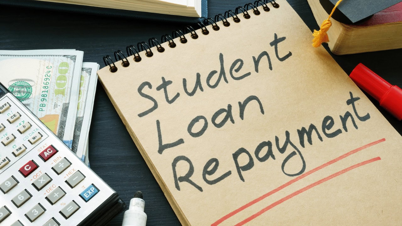 Notebook with 'Student Loan Re-payment' written, financial documents, calculator, and pen.